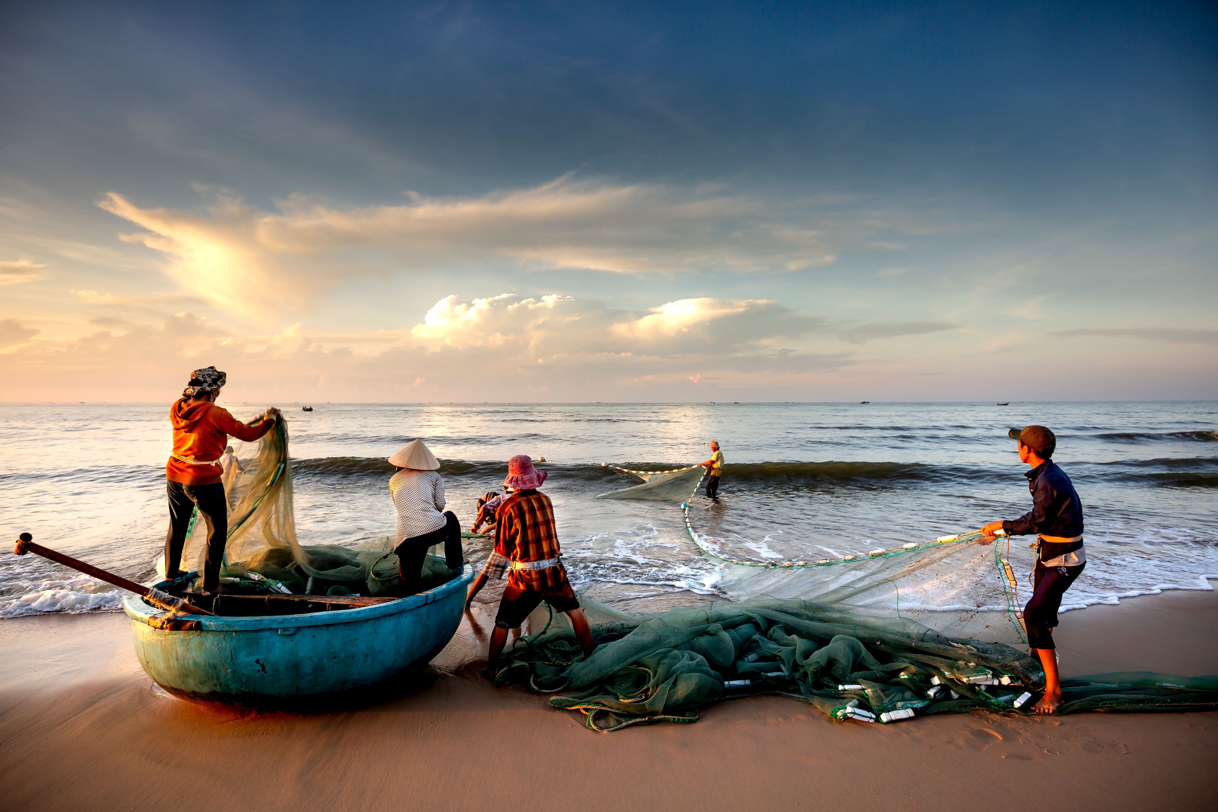 a group of people standing on top of a beach next to a boat